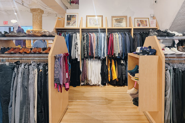 Racks of secondhand clothing with shelves of shoes and accessories inside Housing Works Thrift Shop Chelsea.