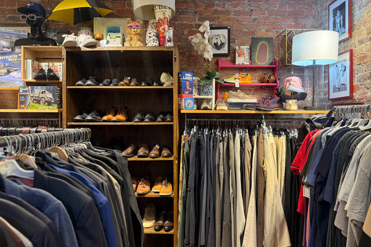 Racks of men’s clothing and shelves of secondhand shoes inside Housing Works Thrift Shop West Village.